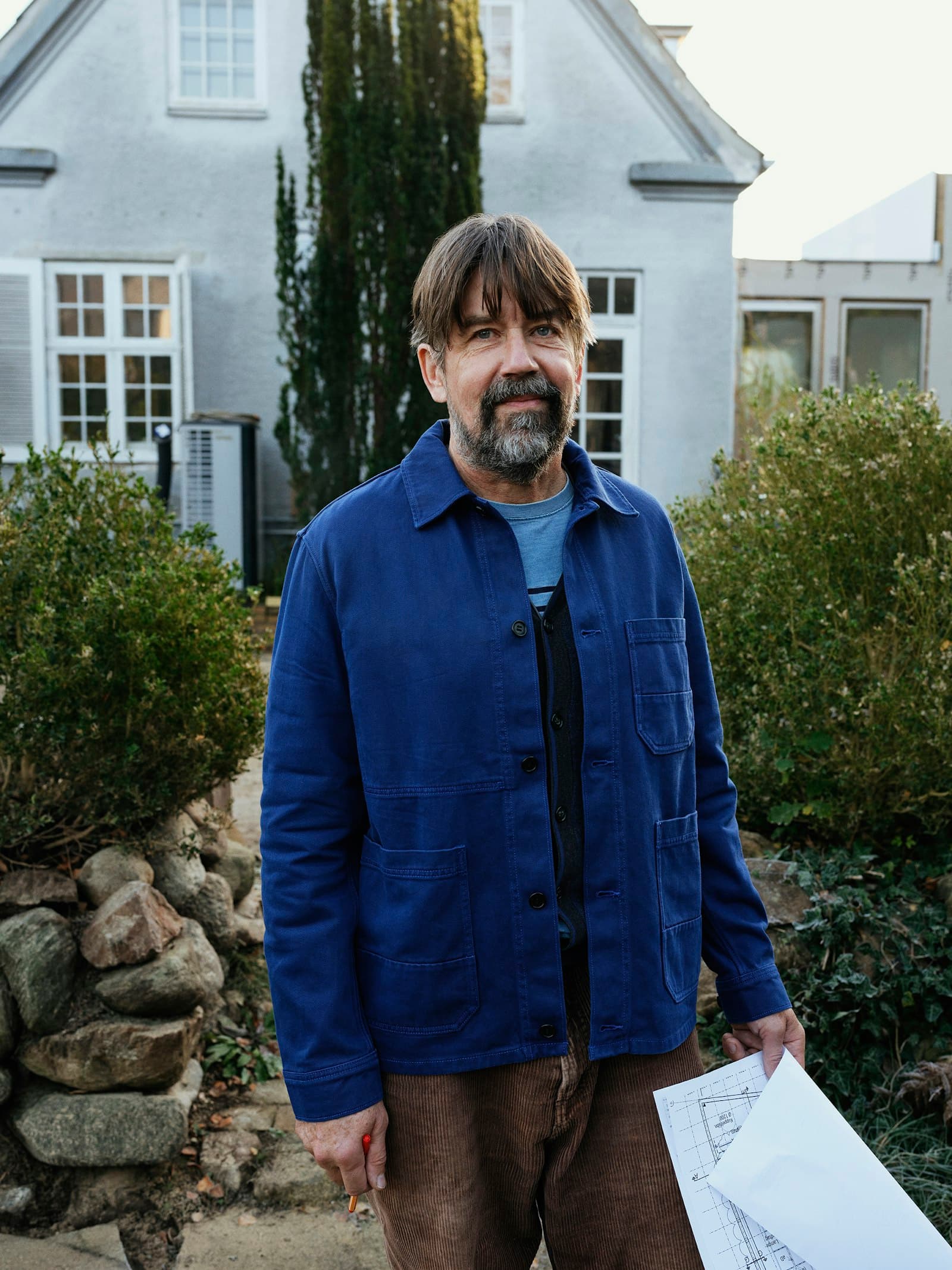 A professional reviewing property plans on-site outside a house